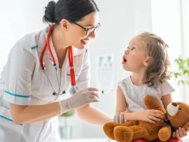 Little girl with teddy bear gets a shot from physician