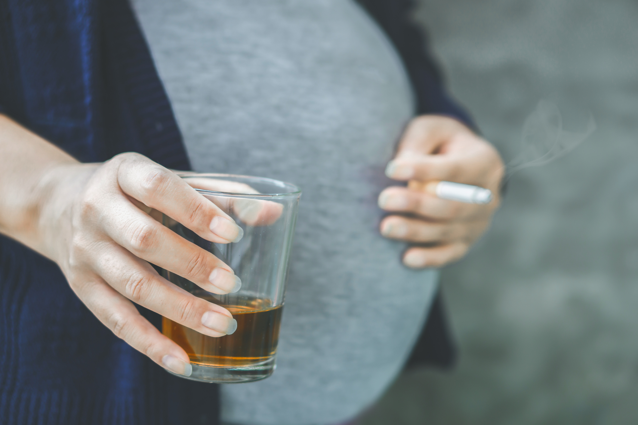 Pregnant woman holding glass of alcohol and cigarette