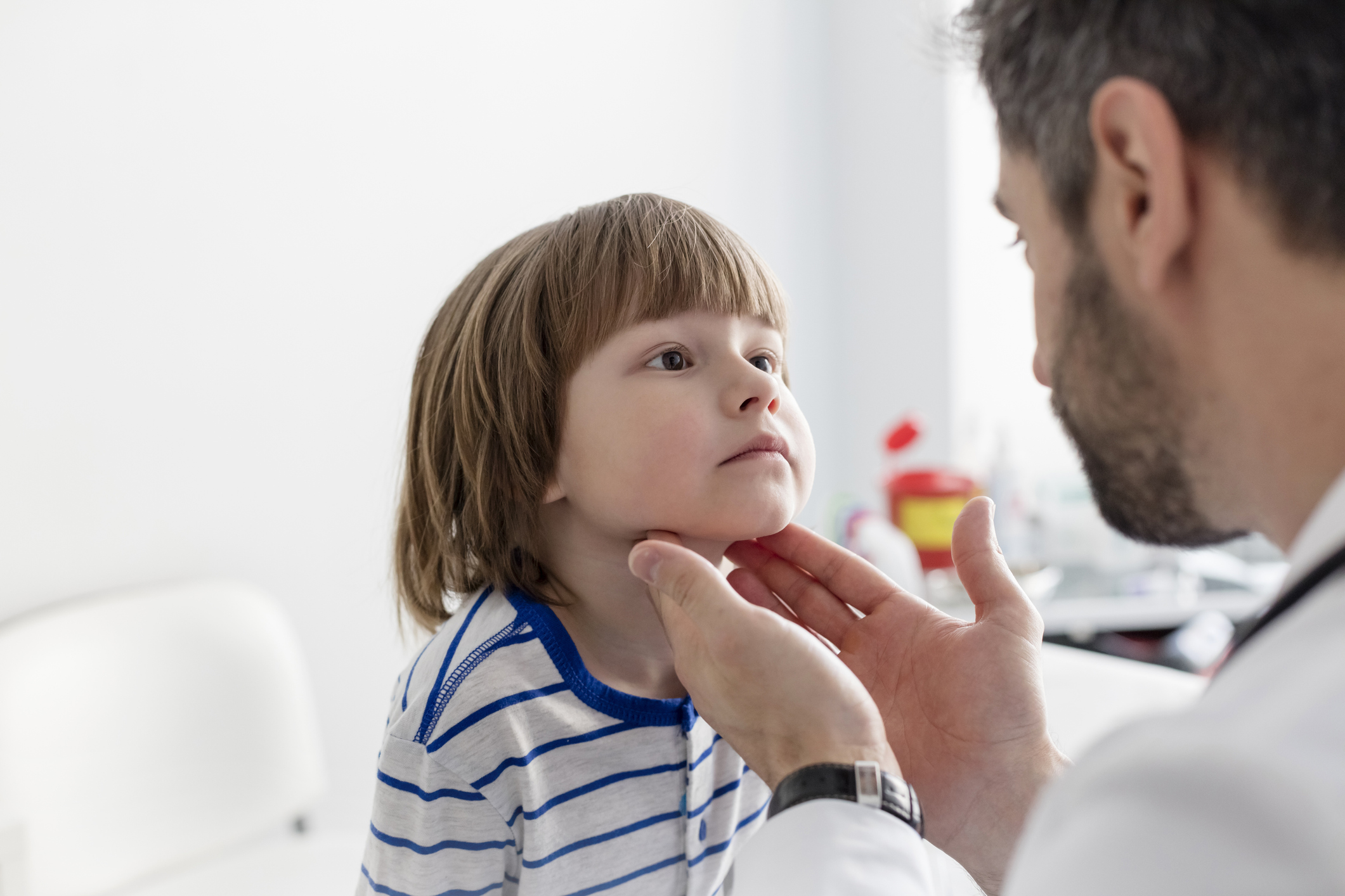 Physician examining young boy's neck