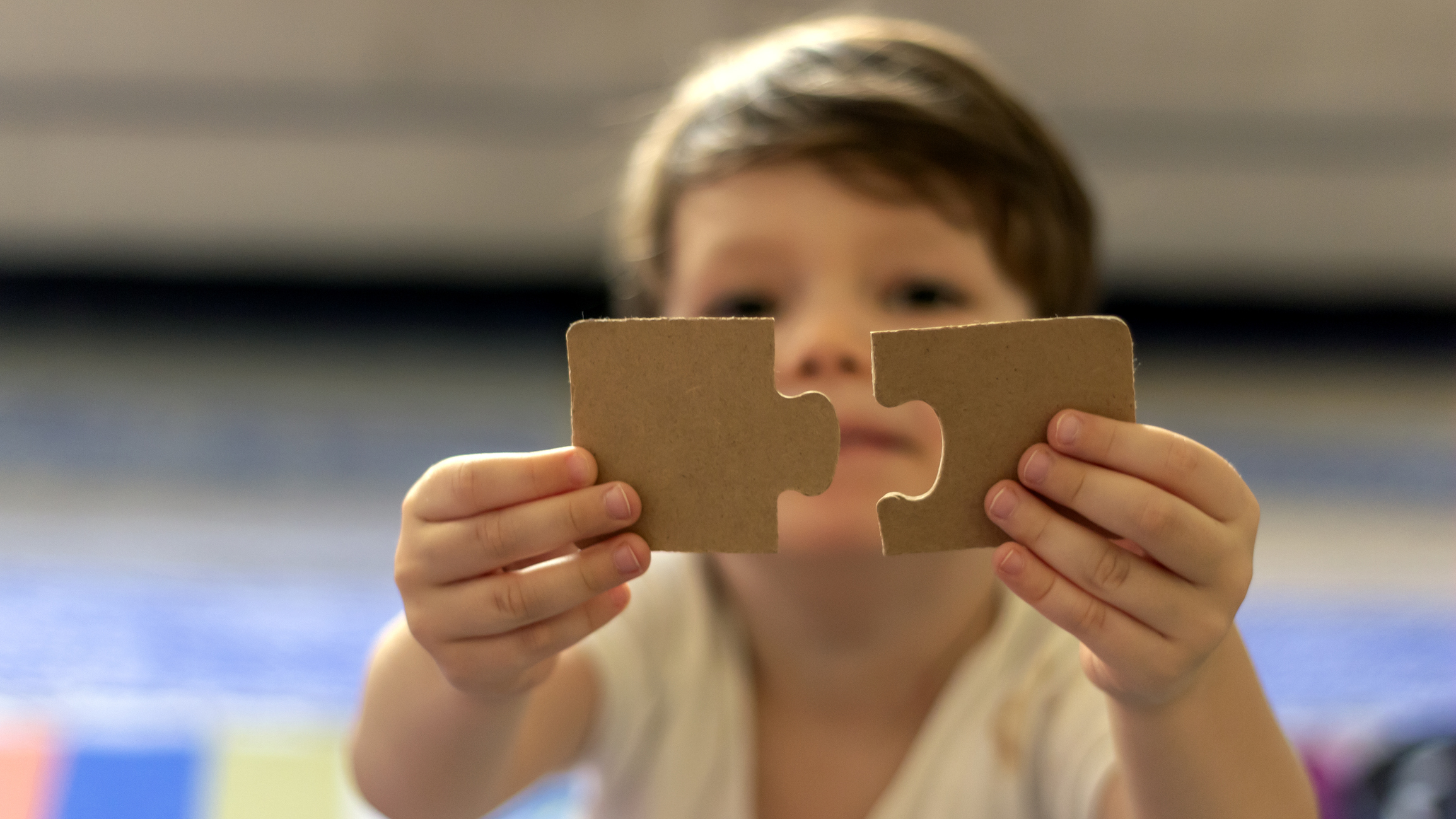 Boy holding up puzzle pieces