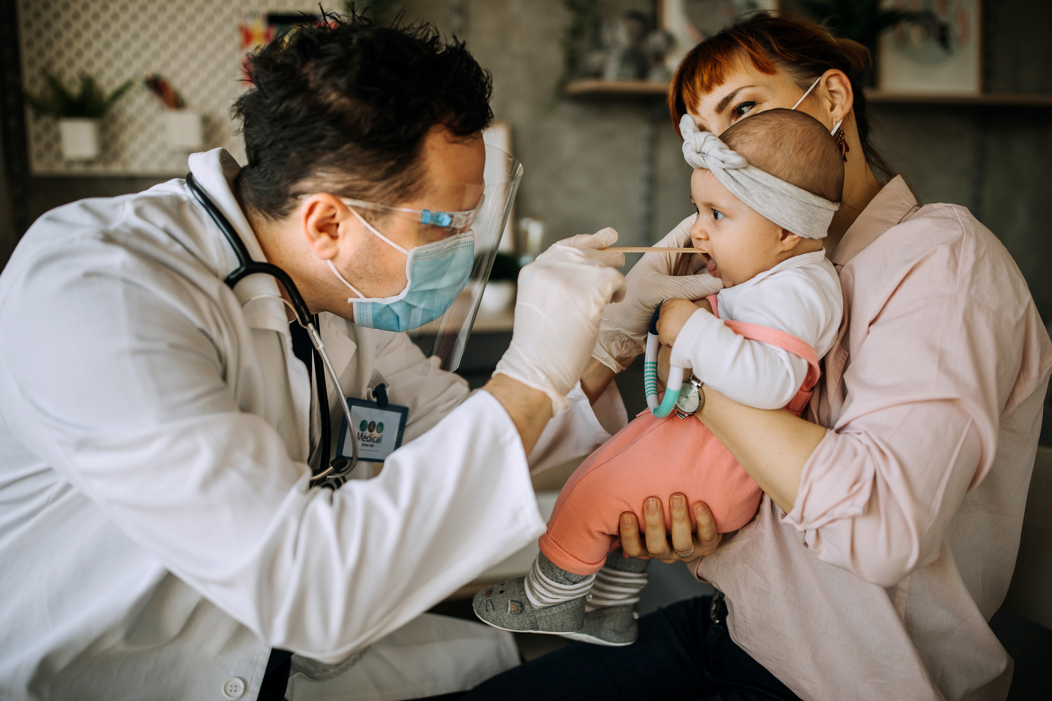 Male pediatrician examining throat of newborn baby