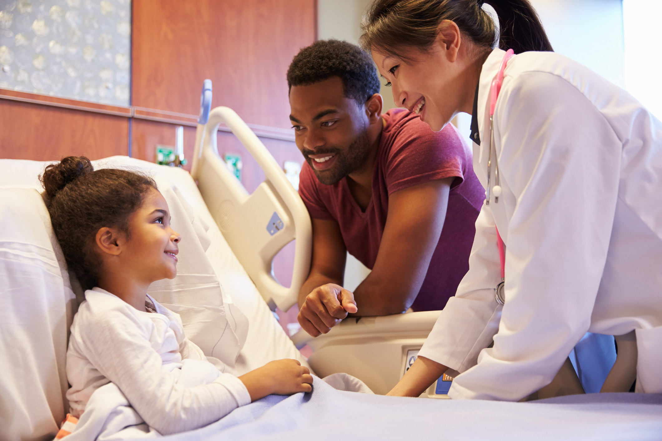 Young girl in hospital bed with nurse and doctor at bedside