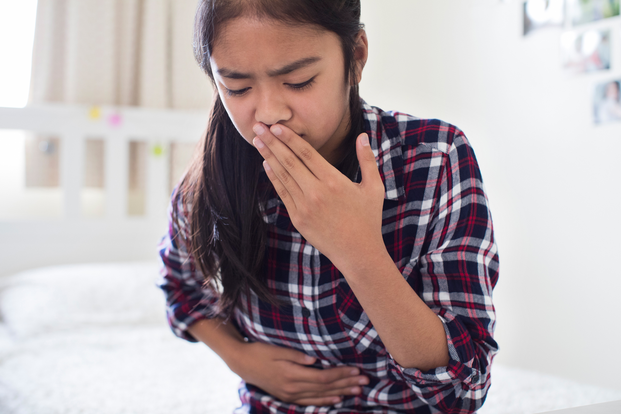 Girl holding stomach with hand over her mouth