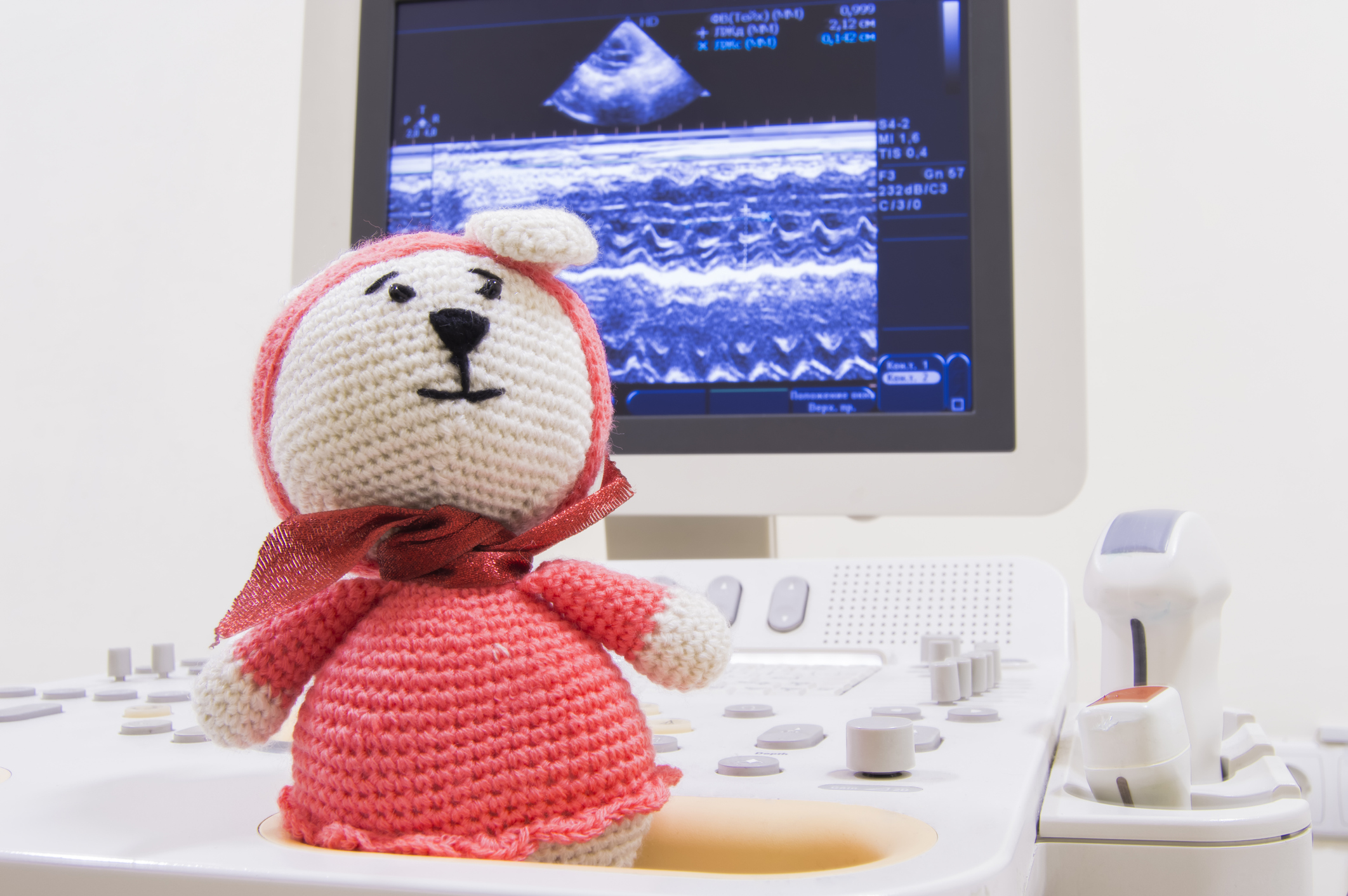 Medical ultrasound scanner and children toy knitted bunny on screen background with waves ECHO heart test or scan and ultrasonic probes.