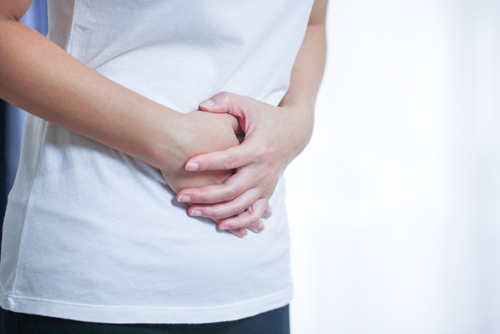 hands holding stomach as if having discomfort image