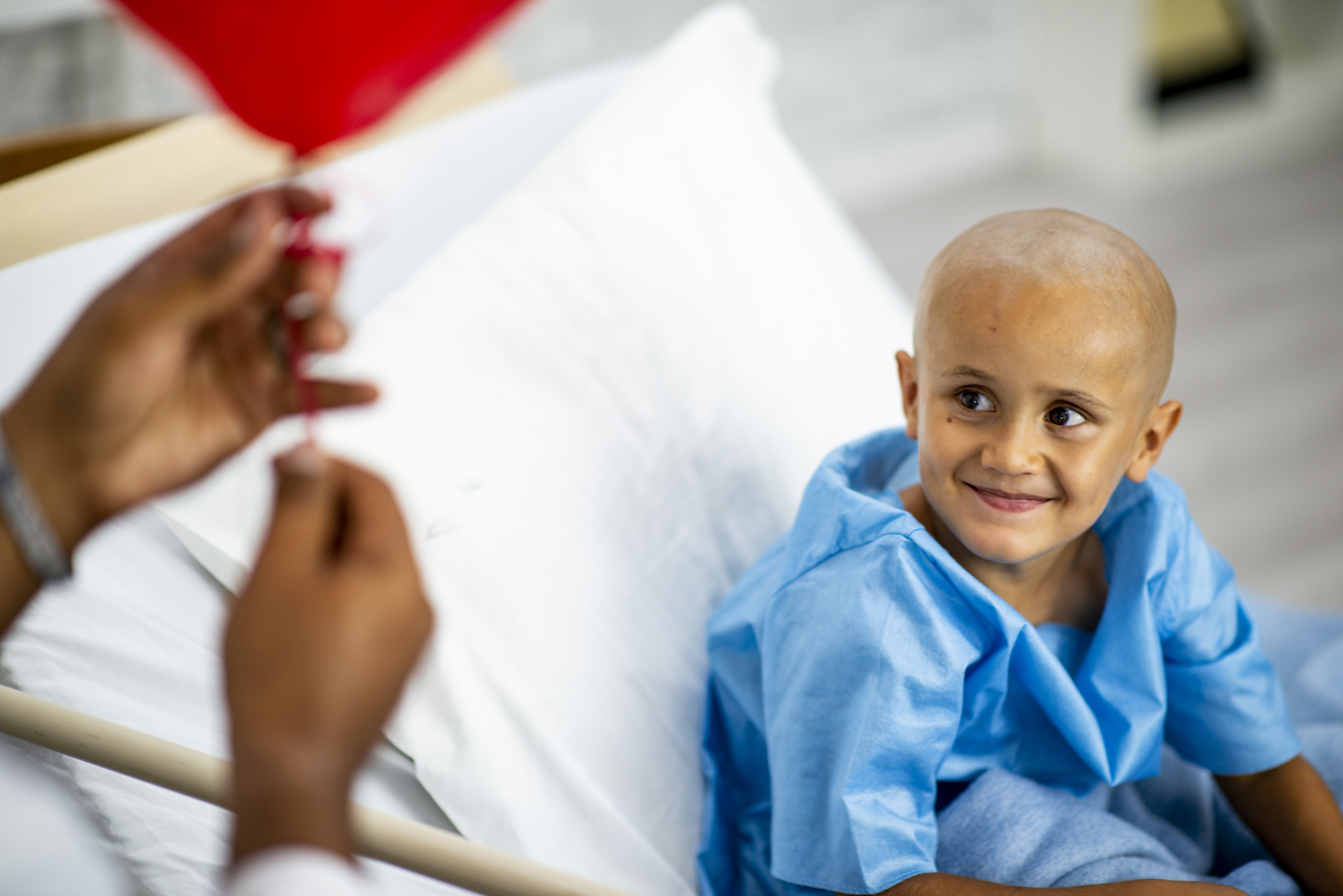 Young boy in hospital bed receiving a balloon