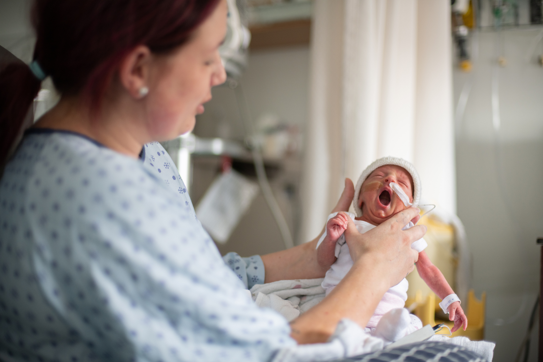 Mother in hospital gown holding baby with oxygen tube