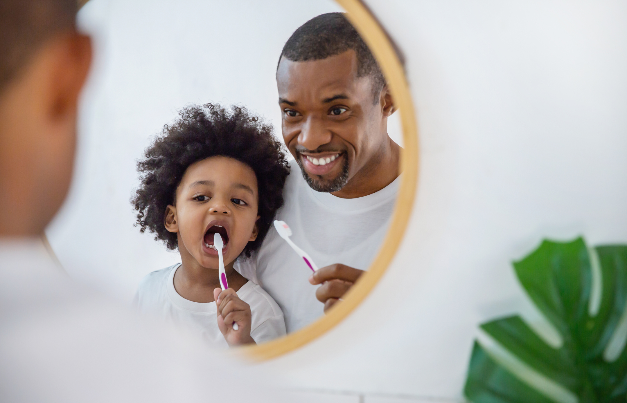 Father helping son brush teeth