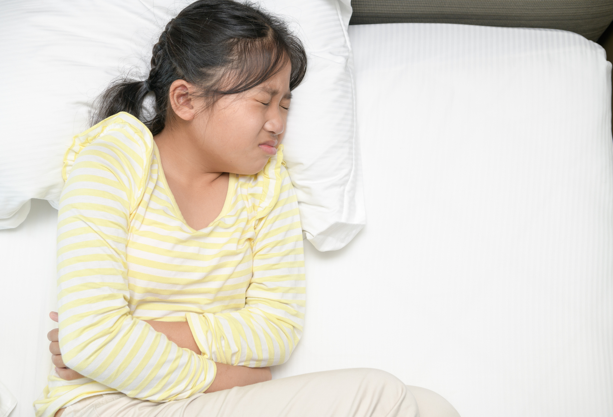 Girl holding stomach lying in bed