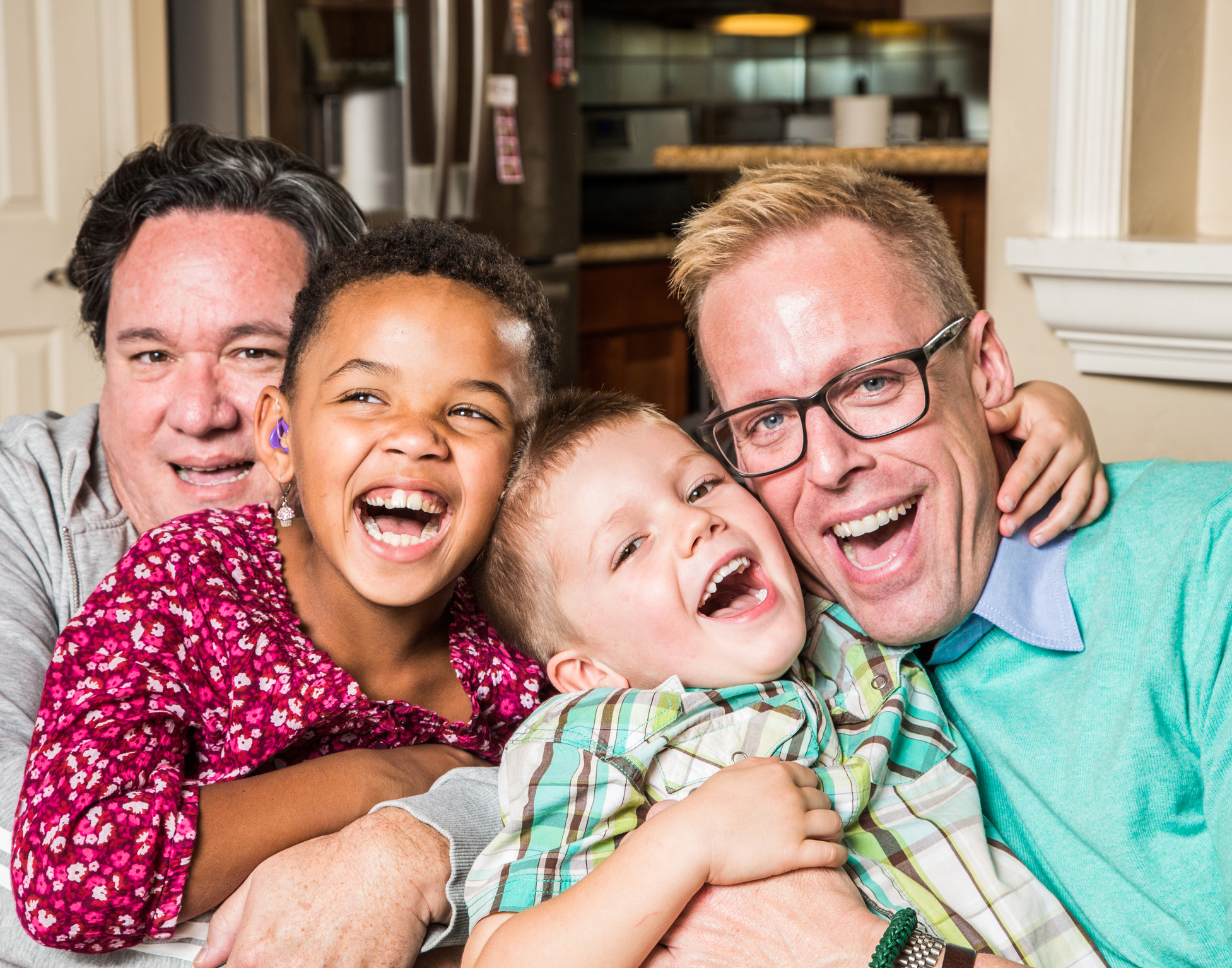 Male parents with two boys, one has a hearing aid in ear