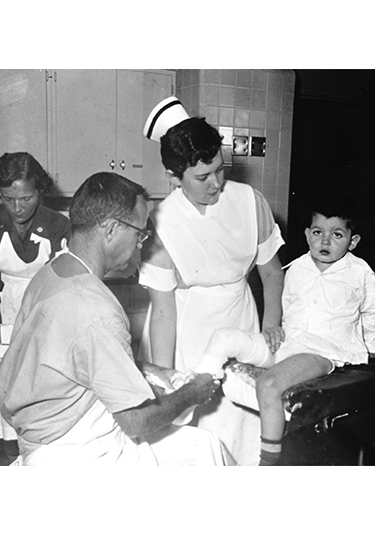 1950 photo of doctor and nurse with young patient with leg wrapped