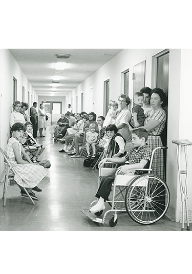 1960 photo of patients and families lining a hallway