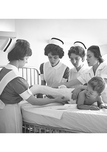 1960s photo of student nurses caring for a pediatric patient