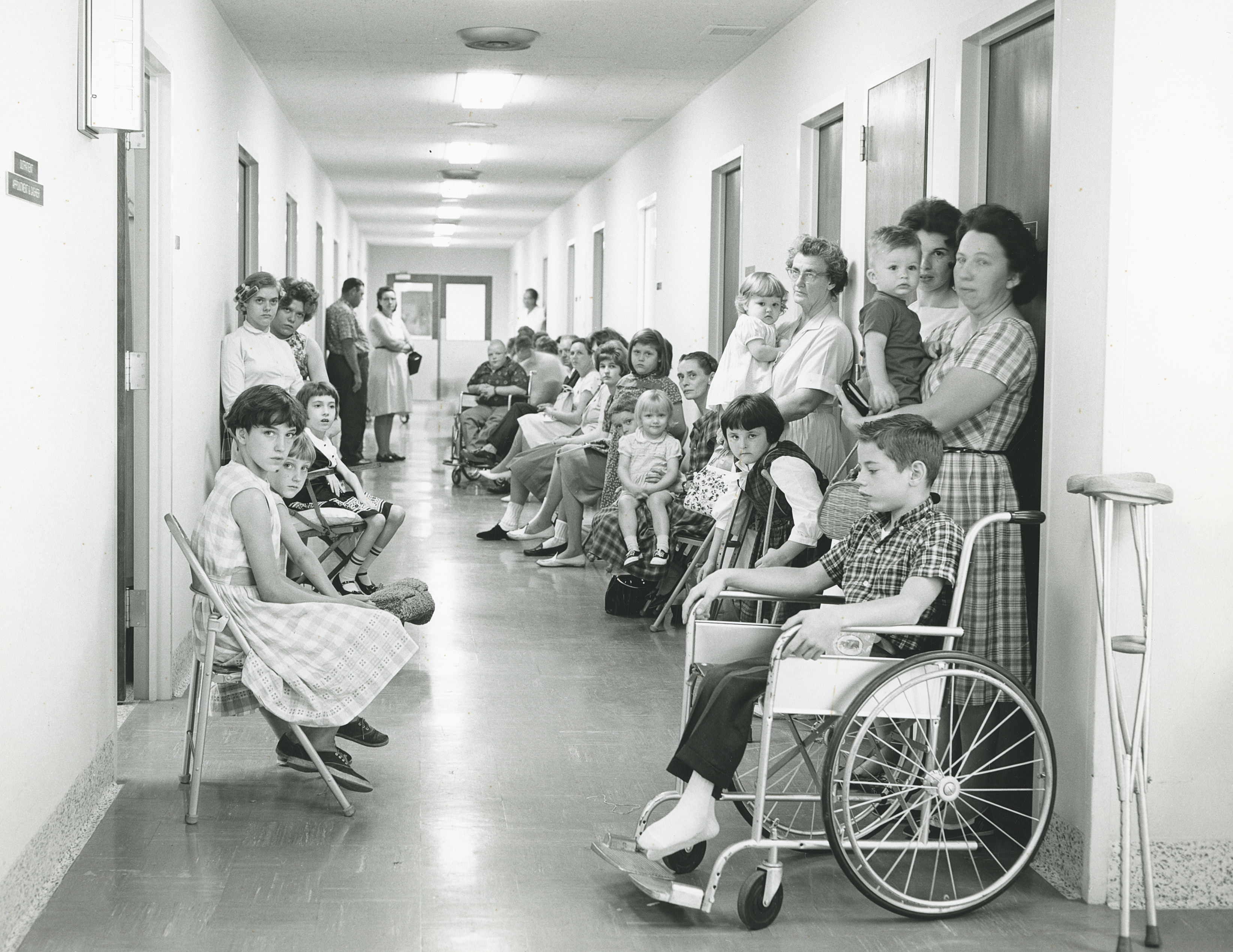 1960 photo of patients and families lining a hallway