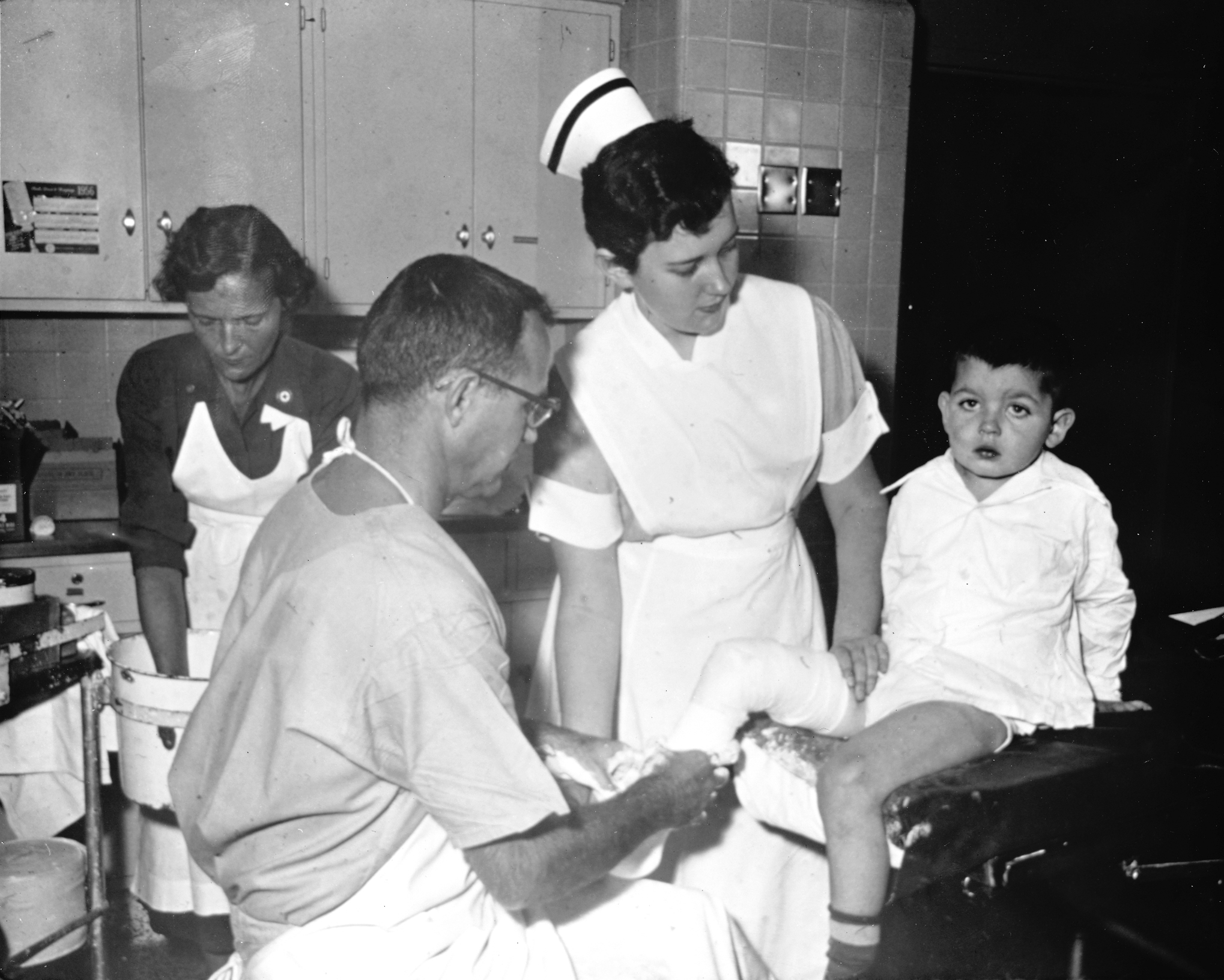 1950 photo of doctor and nurse with young patient with leg wrapped