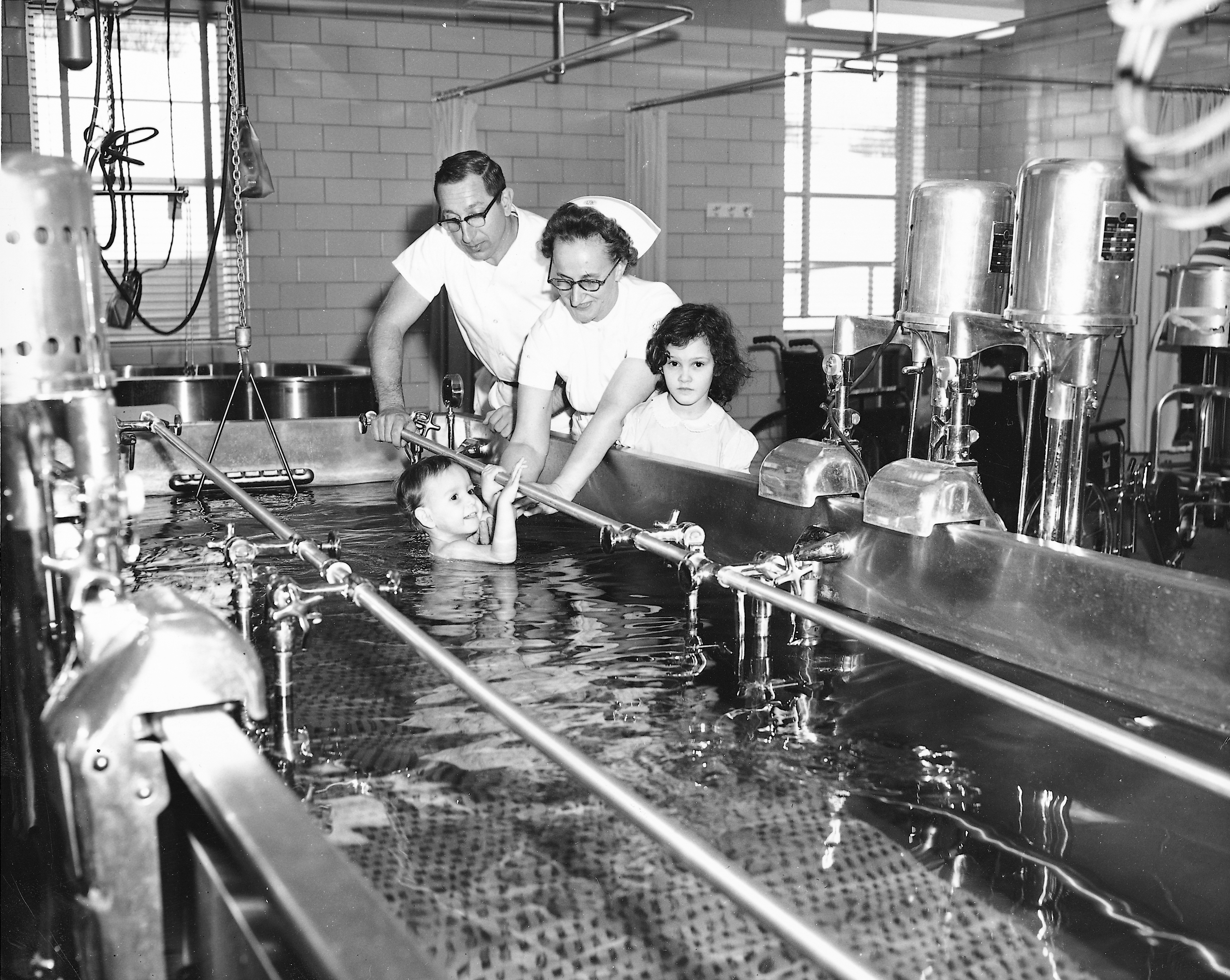 1960s photo of pediatric patient receiving therapy in a pool