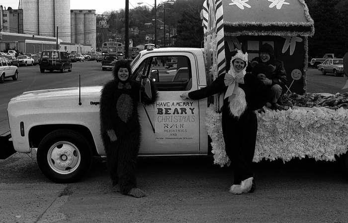 two people in bear costumes standing in front of float