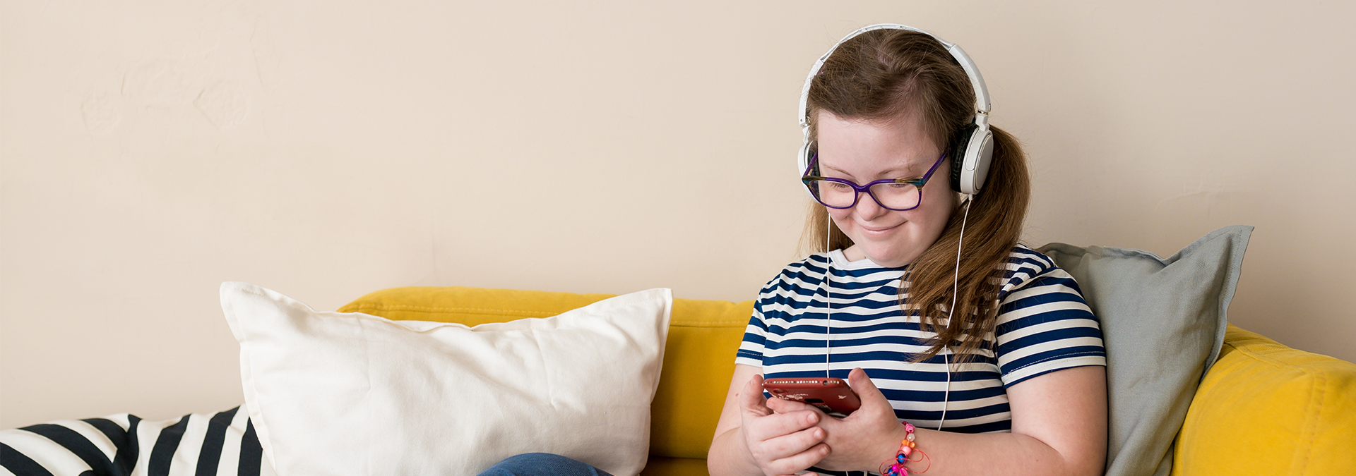 Young girl with Down Syndrome wearing headphones holding a phone