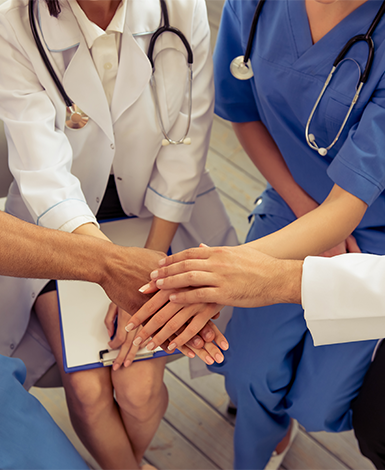 Group of medical providers with hands in middle of a circle