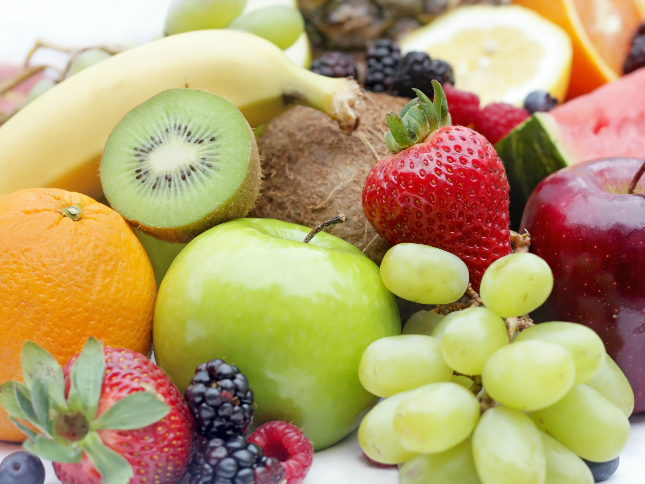 Image of bananas, apples, strawberries and grapes, in a bowl.