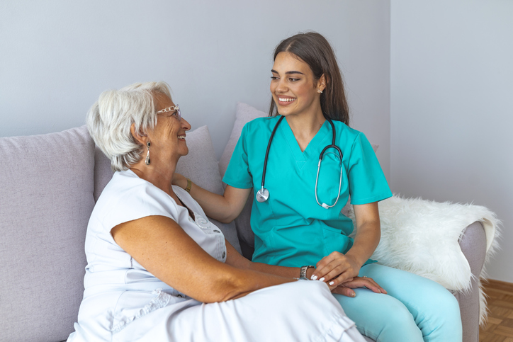 a nurse sitting with a patient smiling