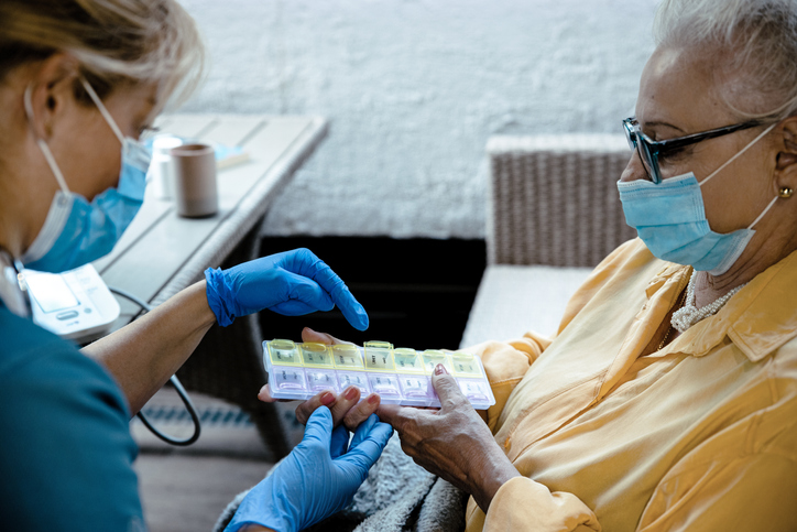 a nurse helping a patient select pills from a pillbox