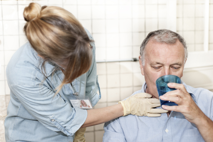 a man drinking water while doctor checks neck