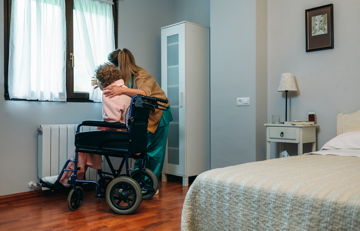 a nurse helping a patient to the window to look out