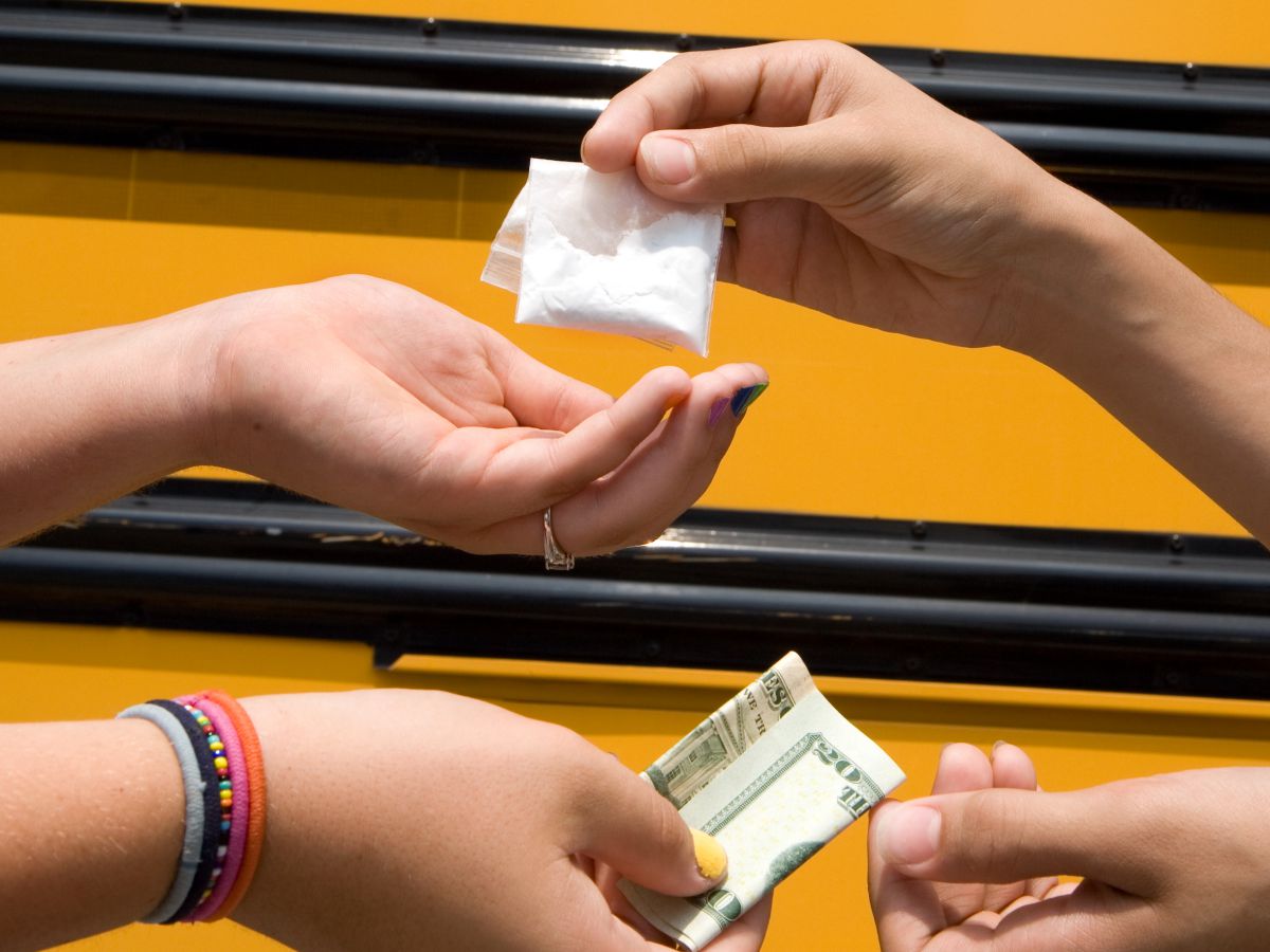 Kids hands in front of a school bus exchanging drugs and money