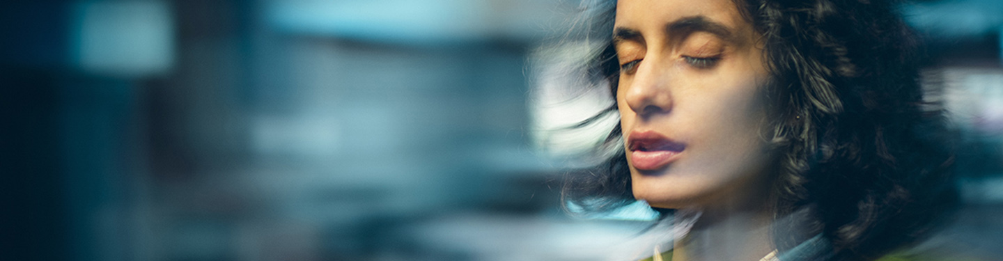 Photo of young business woman who is dizzy with eyes closed while holding a phone