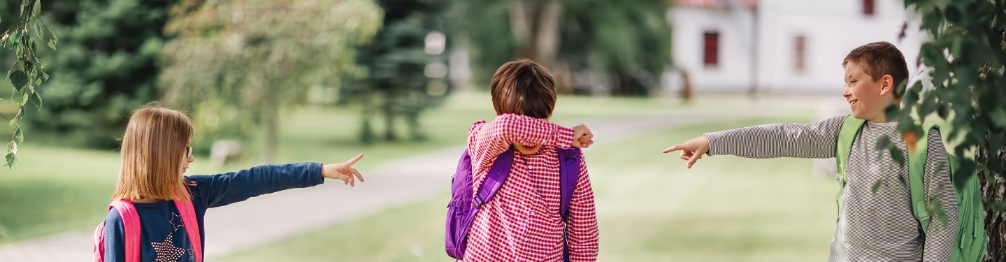 stock photo of two children pointing at a third child indicating bullying