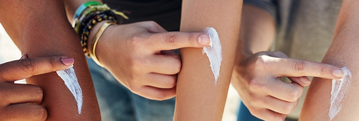 closeup of a line of teens' arms applying dollops of sunscreen