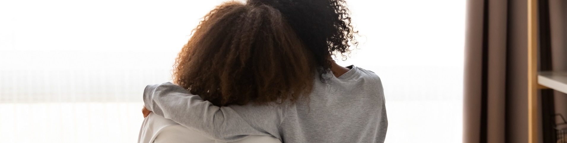 view from behind of parent and child embracing while looking out window