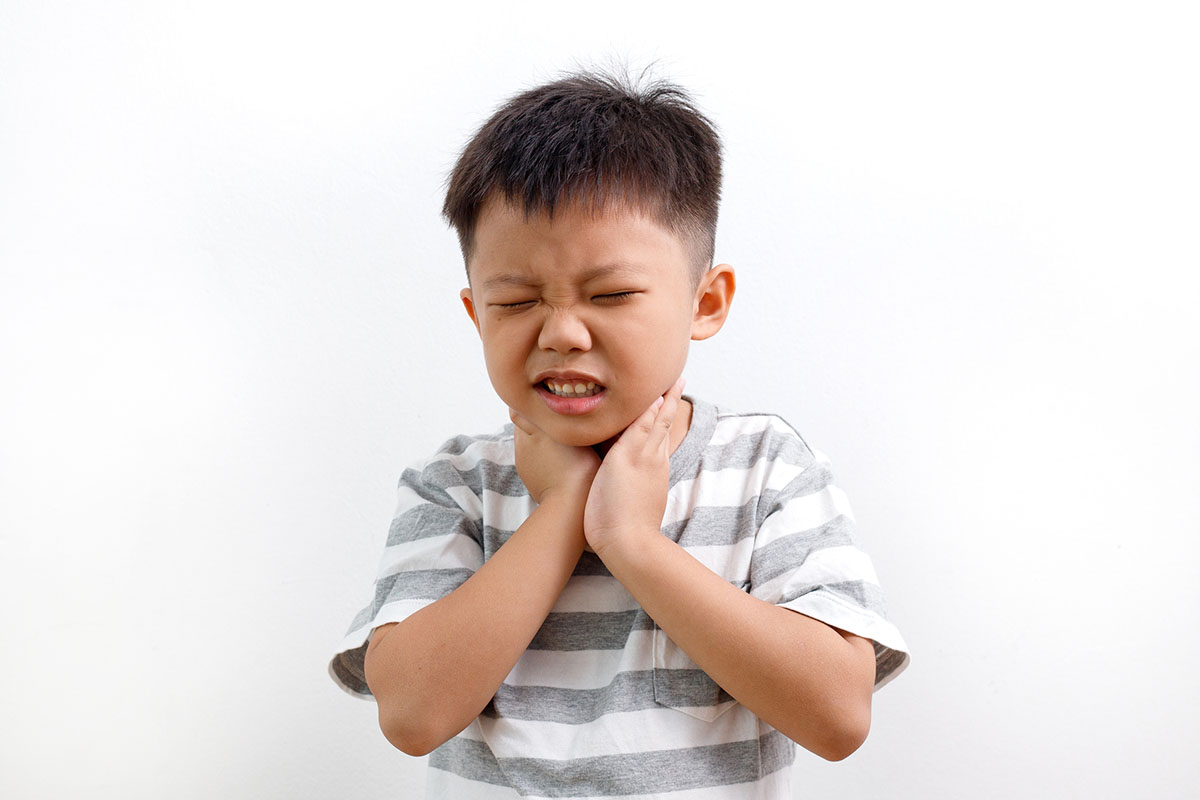Young boy holding his throat in pain