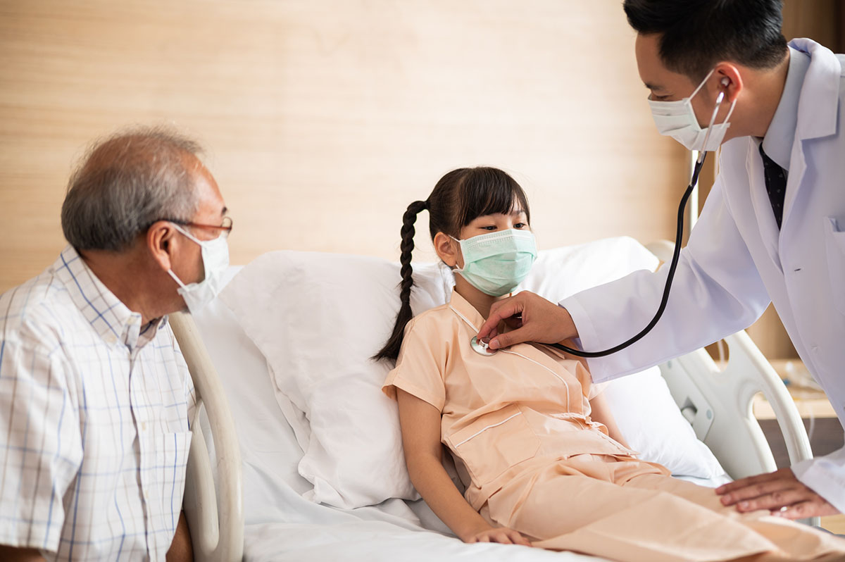 Asian male Doctor using a stethoscope listen to the heartbeat of a little girl patient