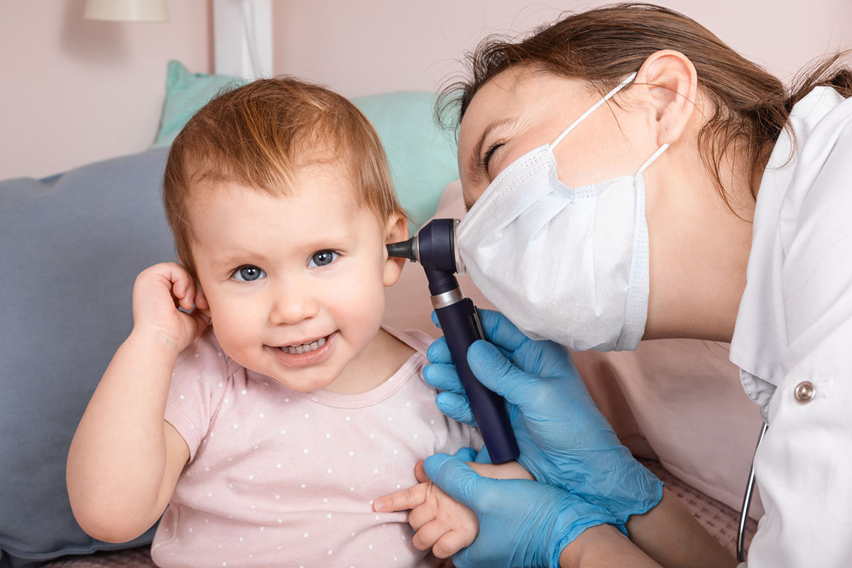 Female doctor looking into young girl's ear