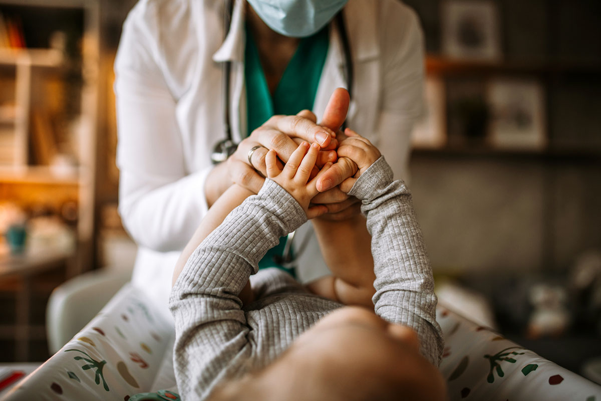 Doctor holding feet and hands of a little baby boy