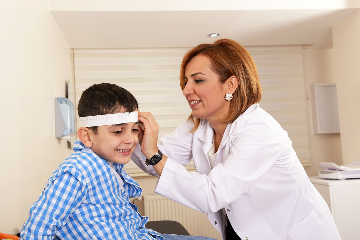Female neurologist taking measurement of boys head