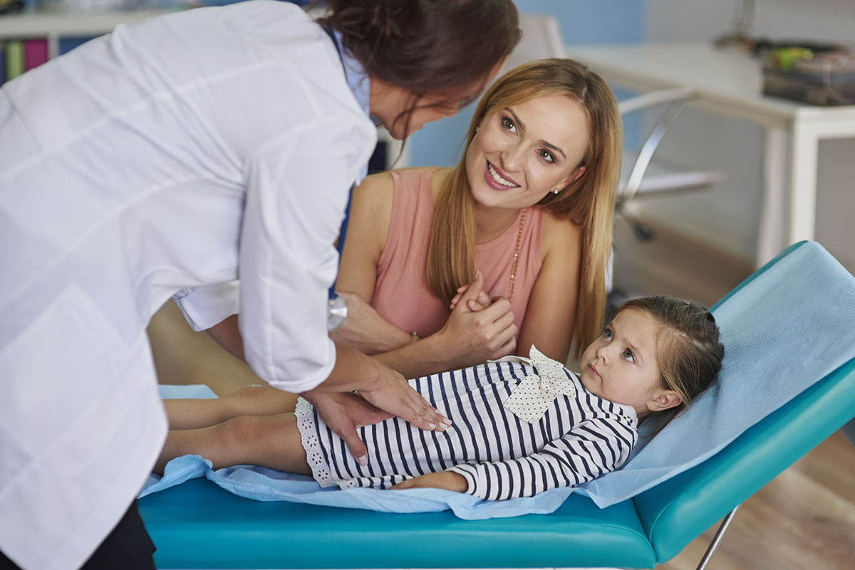 Doctor pressing on young girl's stomach during exam