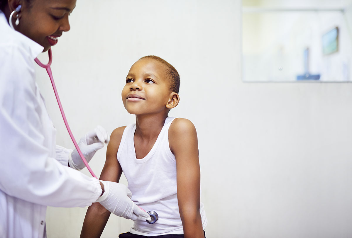 Male doctor listening to young boys stomach with stethoscope