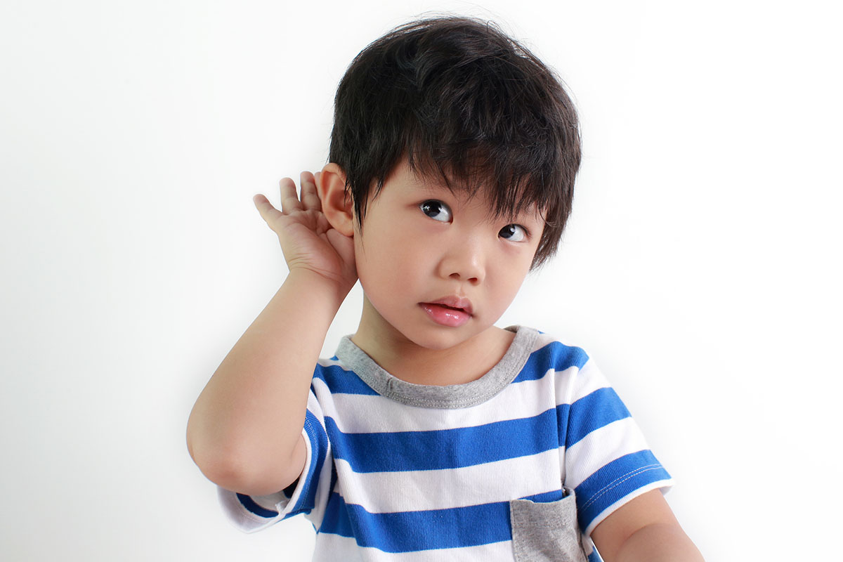 Young boy holding ear listening