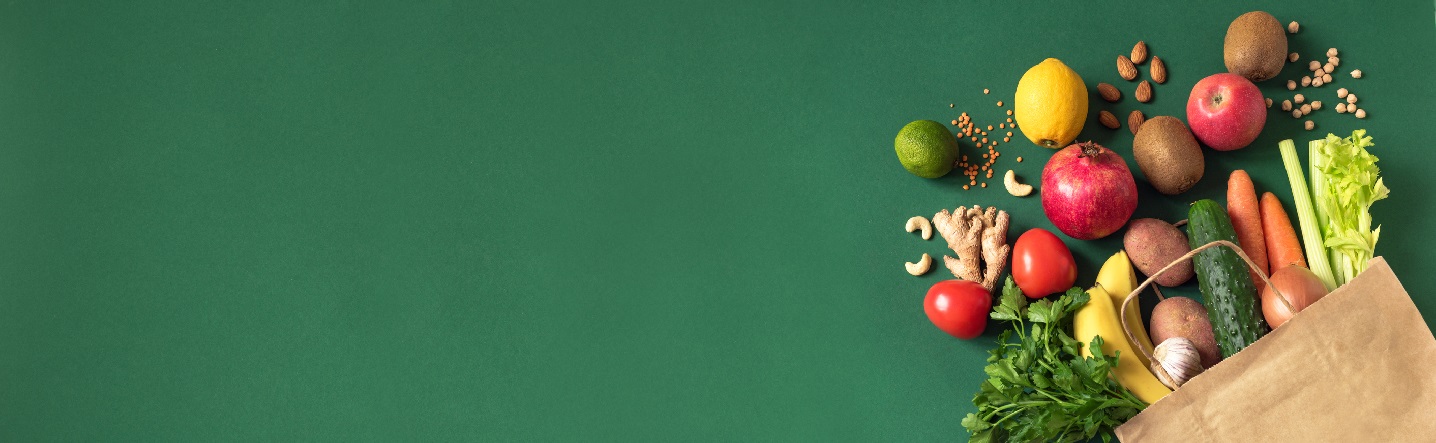 stock image of healthy foods spilling out of paper grocery bag on green background