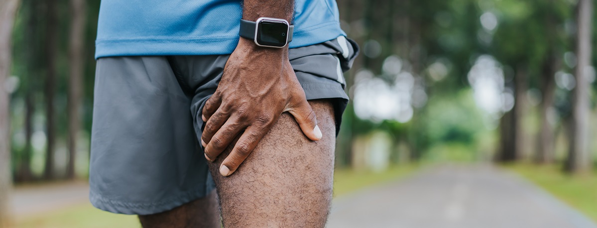 rear view of man walking outside holding his upper leg indicating sciatica pain