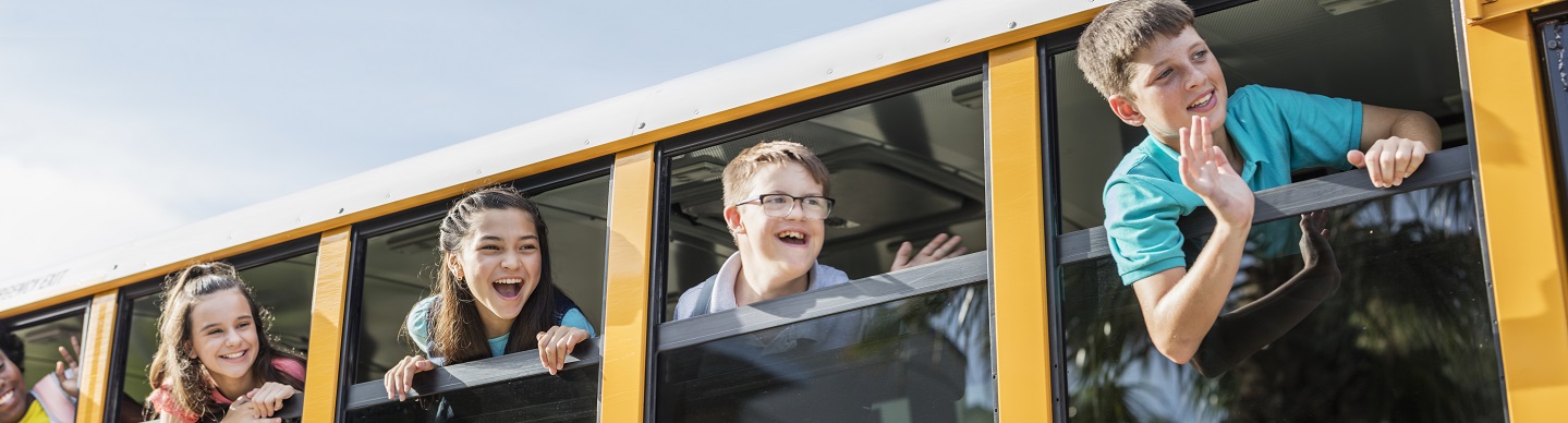 stock image of smiling adolescents looking out school bus windows