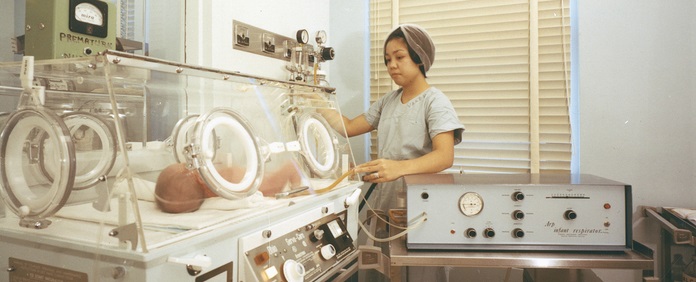 historical photo of Carilion Clinic nurse checking on an infant using an Arp respirator