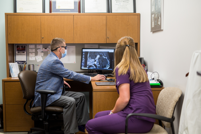 Dr Marvin with team member and brain image on computer 