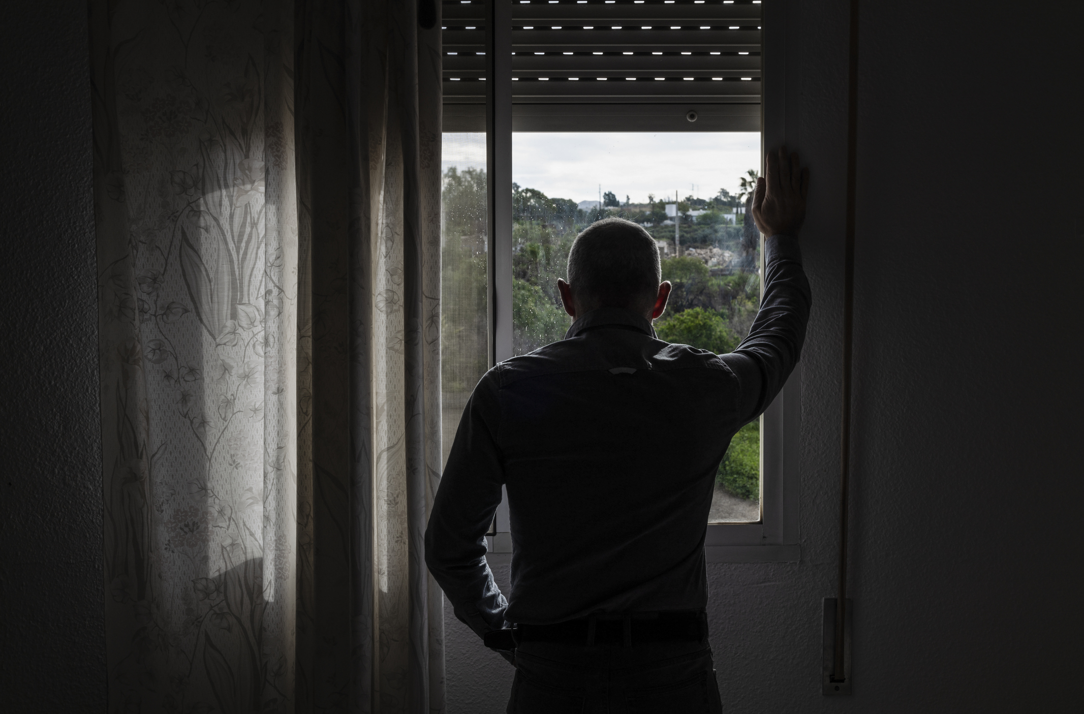 Man with back to camera looking out a window