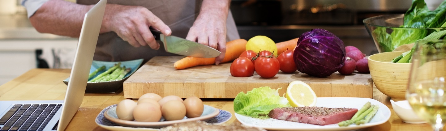 stock image of man preparing healthy foods with laptop nearby