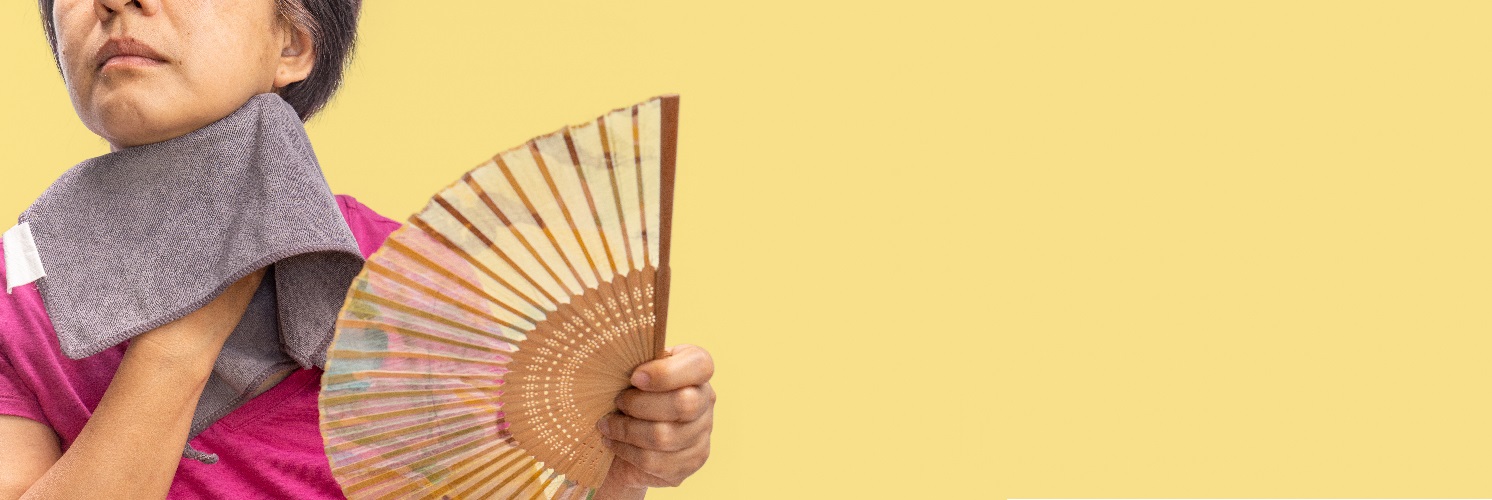 stock image of woman holding fan indicating menopause hot flash