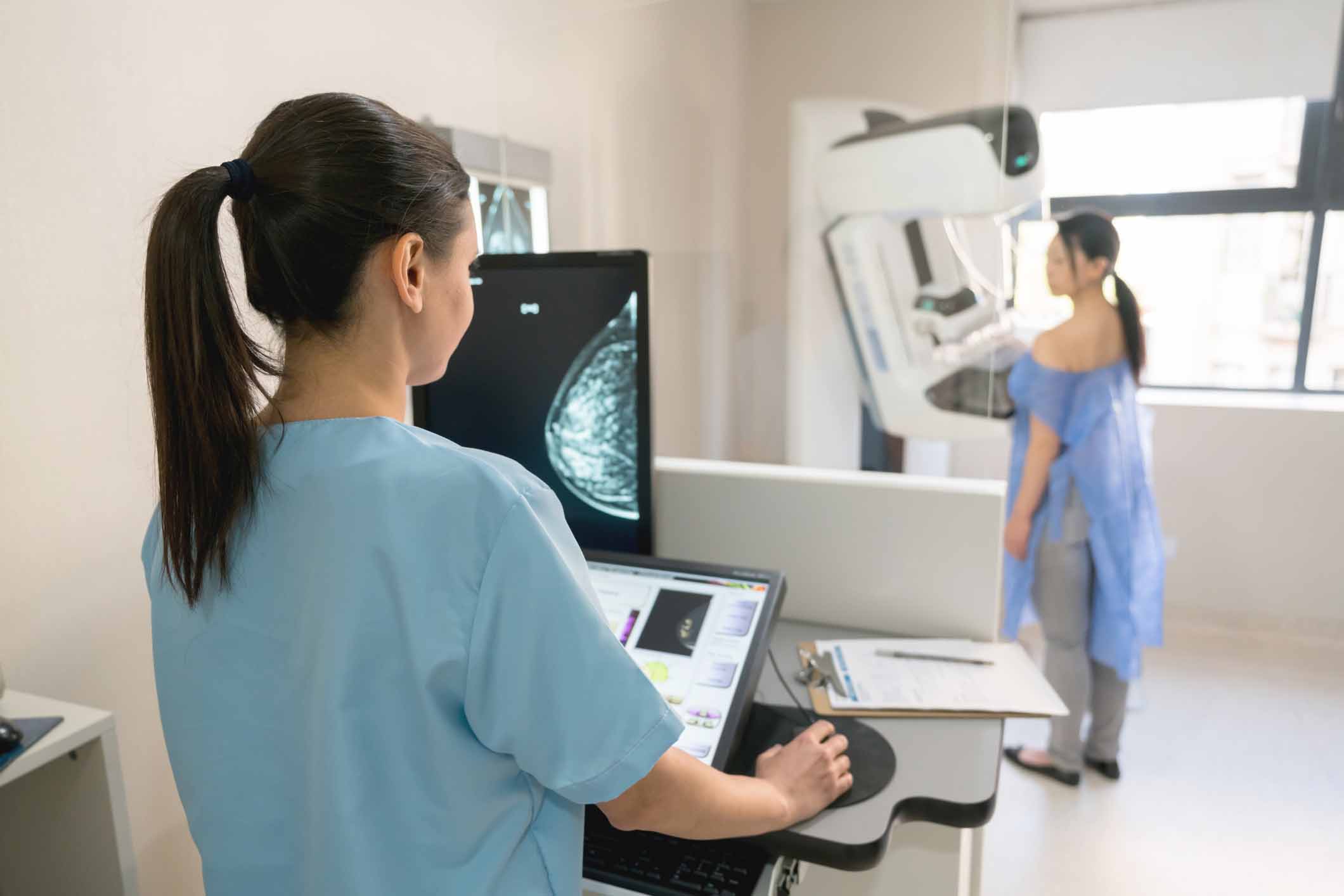 Mammographer and woman getting mammogram